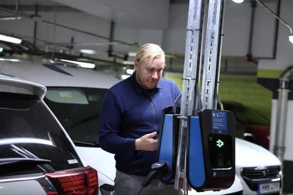 en person i ett parkeringshus med mobil i handen som ska betala parkering